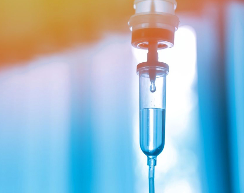 IV drip with blue liquid hanging against blurred medical background in clinical setting