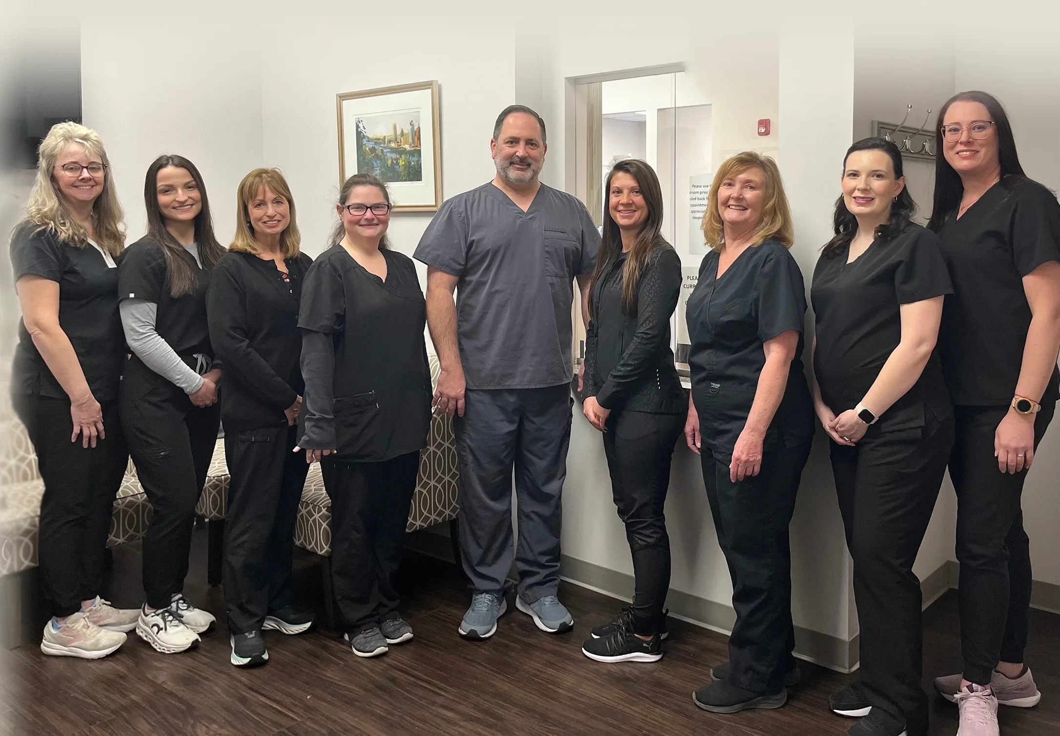 McMurray Family Dental team members posing together in office hallway wearing black uniforms.
